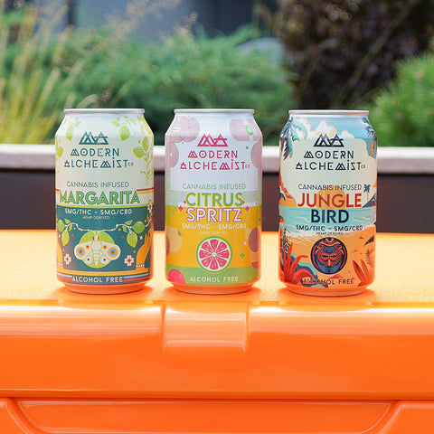 Cans of Variety Pack of Modern Alchemist Cannabis Infused Mocktails including Citrus Spritz, Jungle Bird, and Margarita on top of a cooler. Alcohol free.