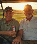 Two smiling men sit in a golf cart at sunset, with one holding a can of Drinkin’ Buds Rum Punch Double Shot, enjoying a relaxed moment on the course.