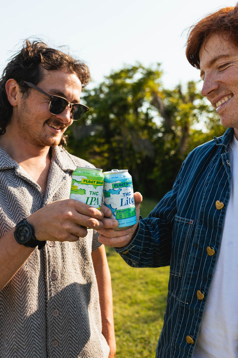 Two people holding cans of Float House in a field
