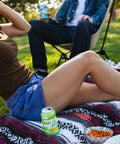 Two people sitting on a blanket outdoors with snacks and drinks and a can of Float House IPA