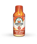 A standalone bottle of Drinkin’ Buds Hot Shot Cinnamon against a white background. The bottle is red and orange with flame graphics, a cannabis leaf logo, and text stating 10mg THC and 10mg CBD per shot