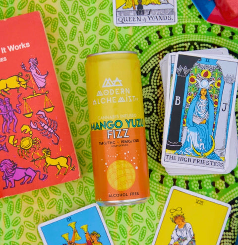 Mango Yuzu Fizz Modern Alchemist Cannabis Infused Mocktail on a towel by the pool with tarot cards surrounding the can. Alcohol free. 