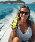  A smiling woman on a boat holds up a can of Drinkin’ Buds Margarita Double Shot, with the ocean and islands in the background.