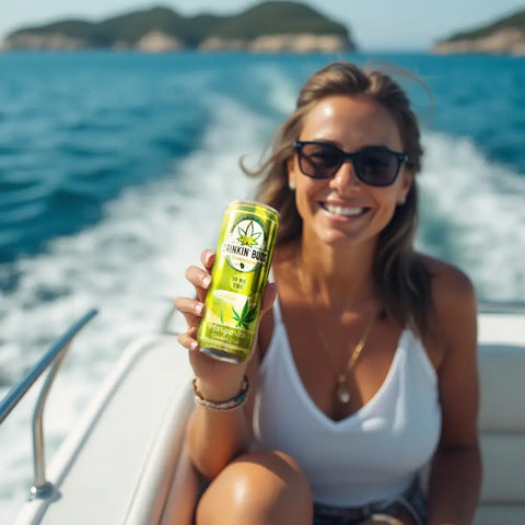  A smiling woman on a boat holds up a can of Drinkin’ Buds Margarita Double Shot, with the ocean and islands in the background.