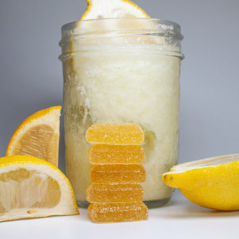 Glass jar with lemonade, lemon slices, and gummy bears on a gray background