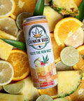 The image showcases a "Drinkin' Buds Beverages" Mai Tai can, surrounded by vibrant slices of pineapple, orange, lime, and lemon. The tropical arrangement highlights the drink's fruity, THC- and CBD-infused essence.
